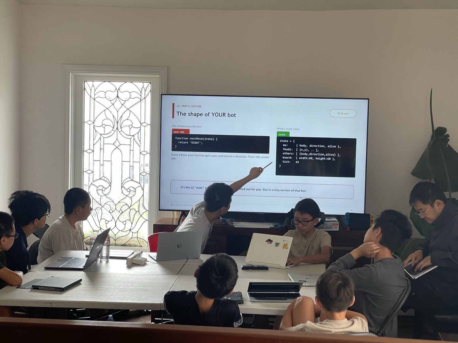 A camper at the bot-anatomy lecture with real nextMove(state) code on the screen